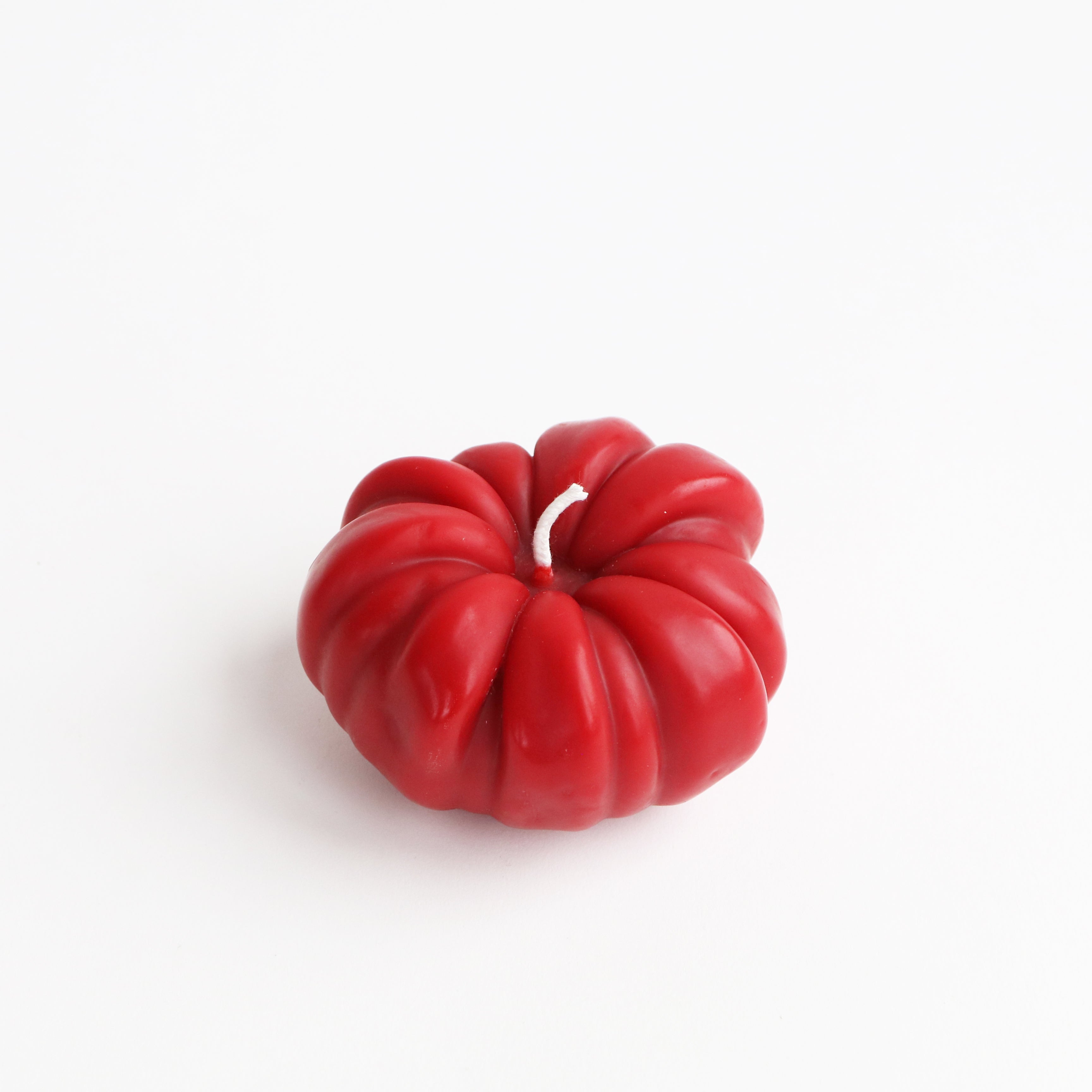 Red tomato shaped candle on a white background