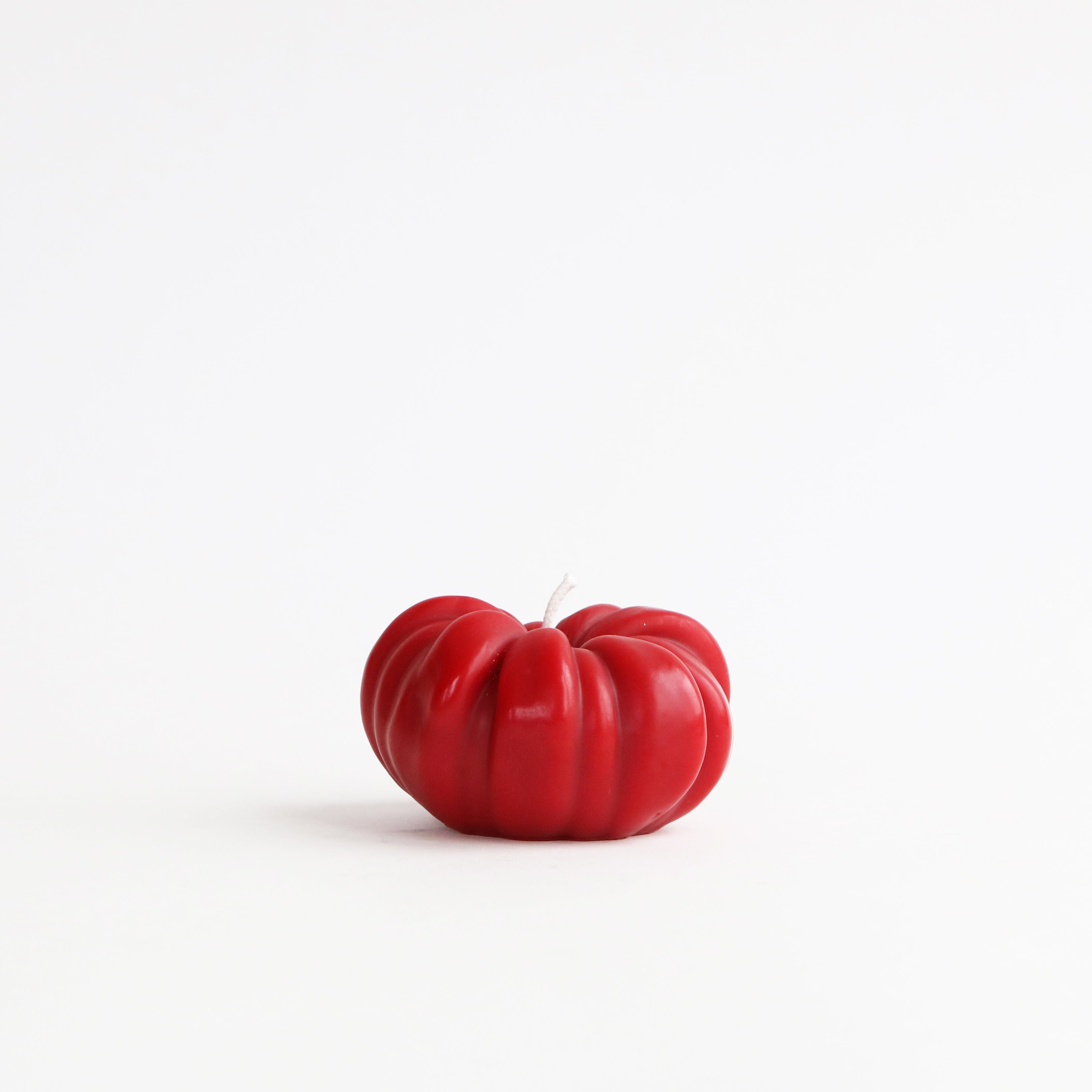 Red candle shaped like a tomato on a white background