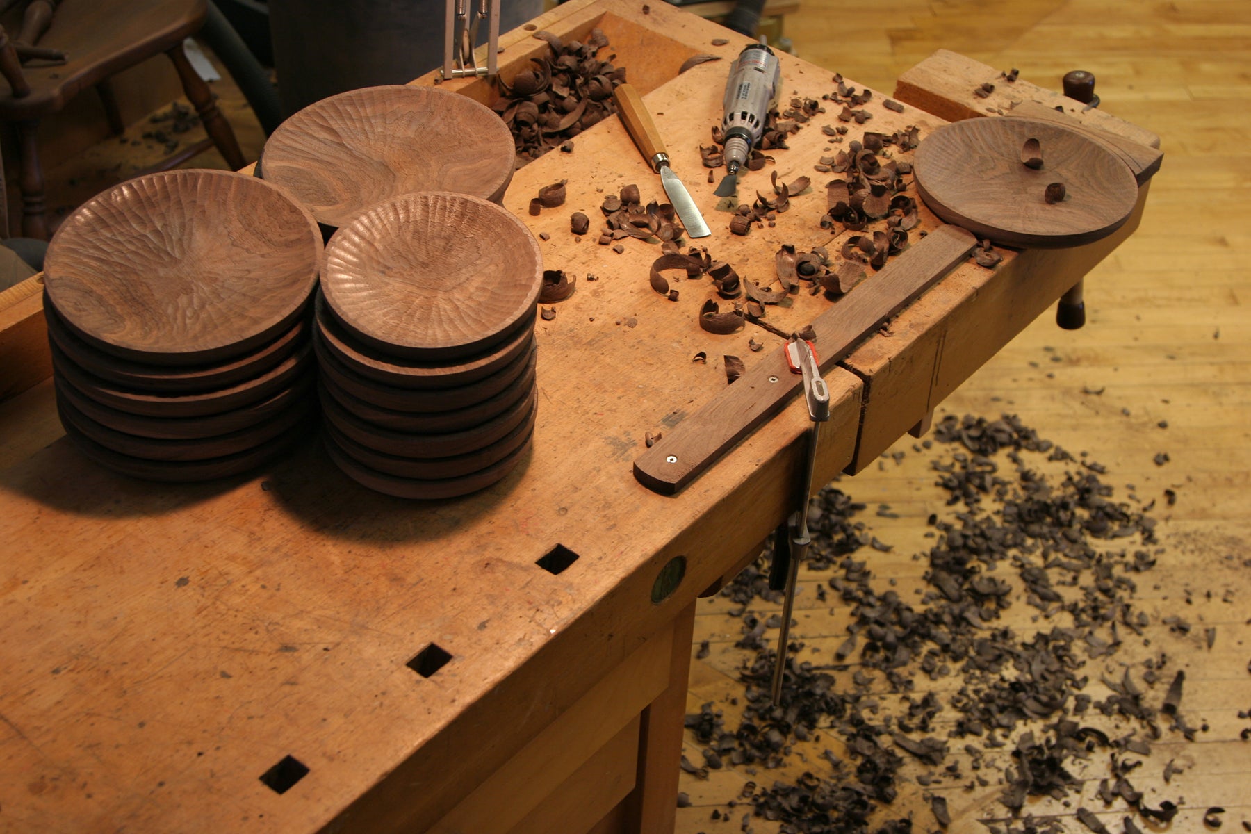 Woodworking workshop with wooden plates and tools on a workbench.