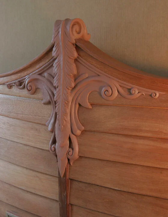 Close-up of an ornate wooden headboard with intricate carvings.