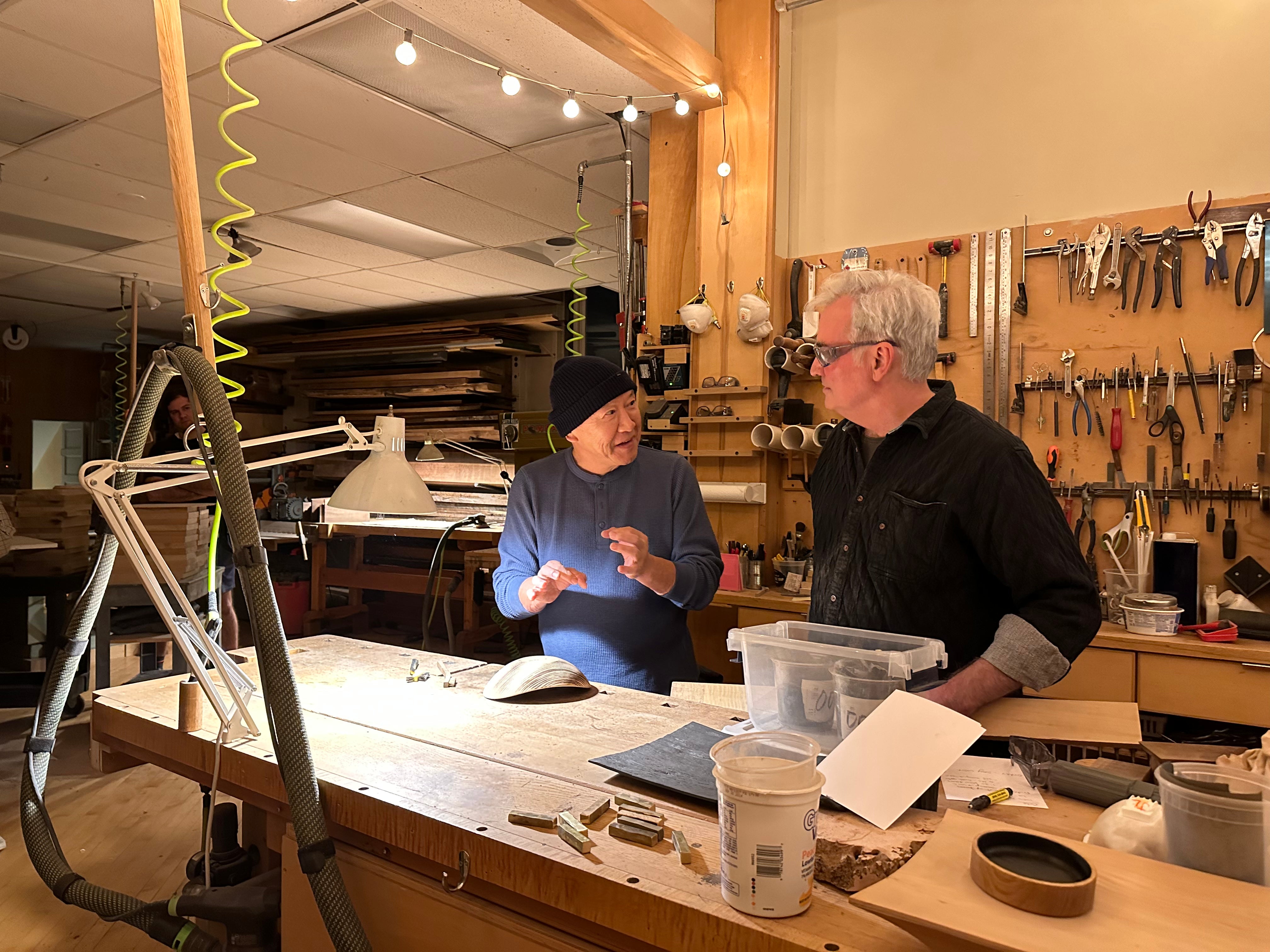 Two men in a workshop discussing tools and equipment.