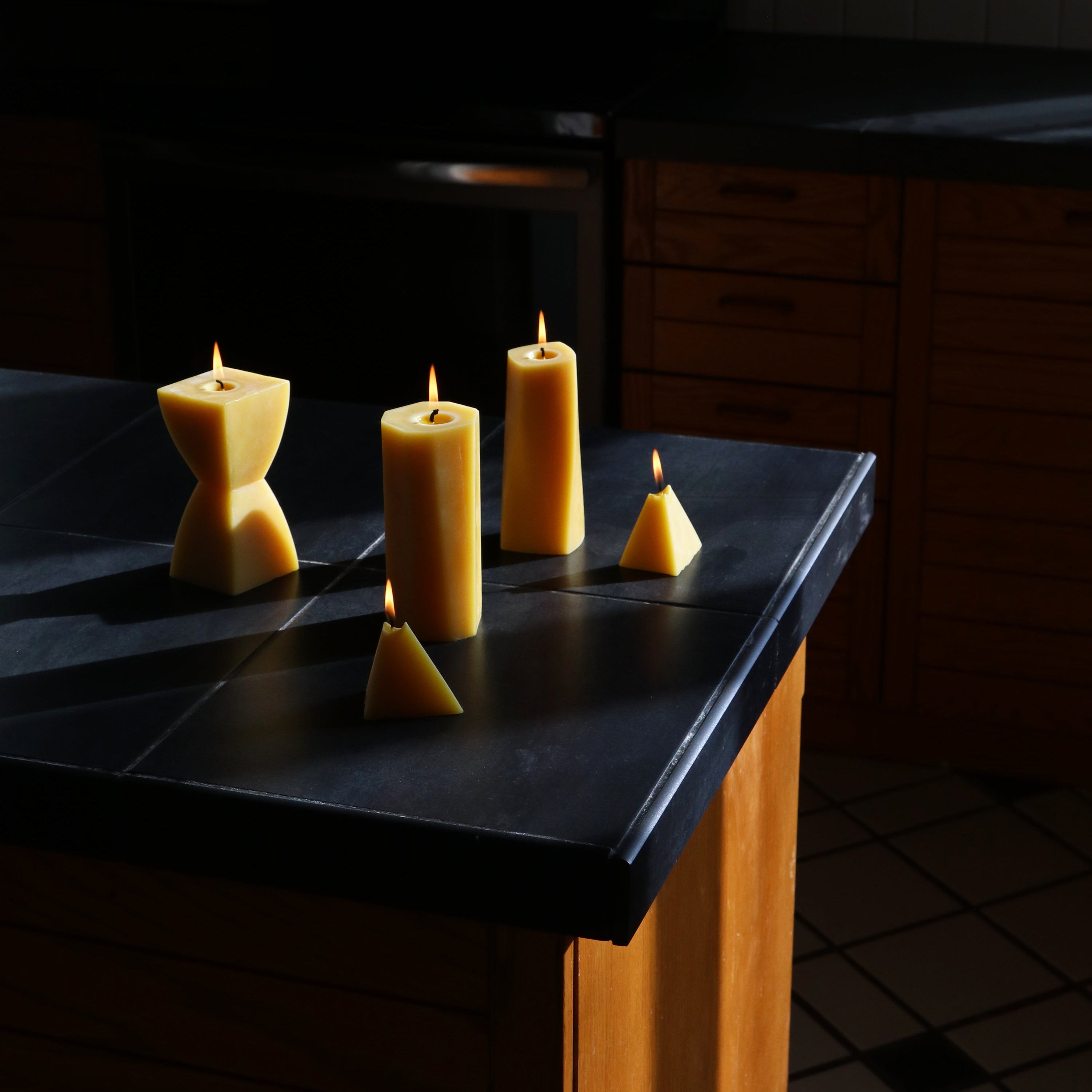 Three candles on a dark surface in a dimly lit room