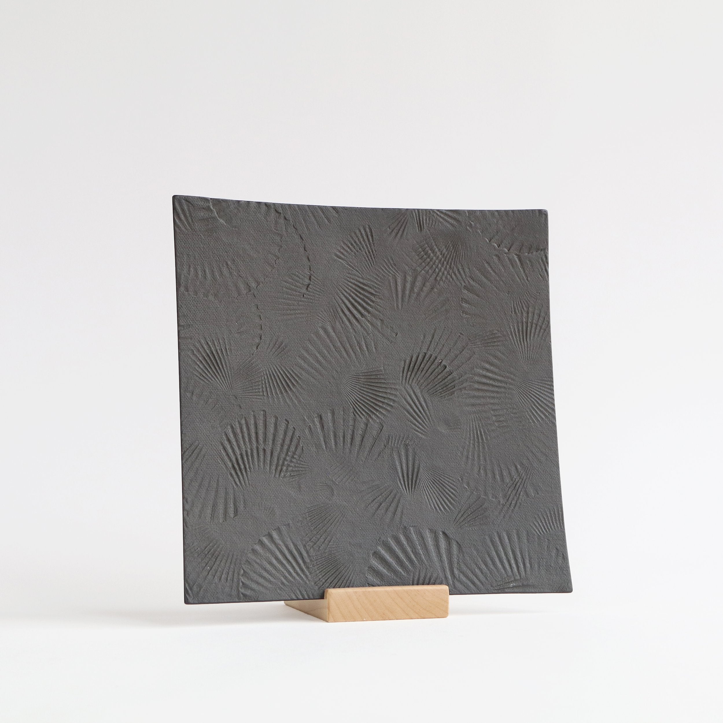 black serving platter with scallop texture of wood stand