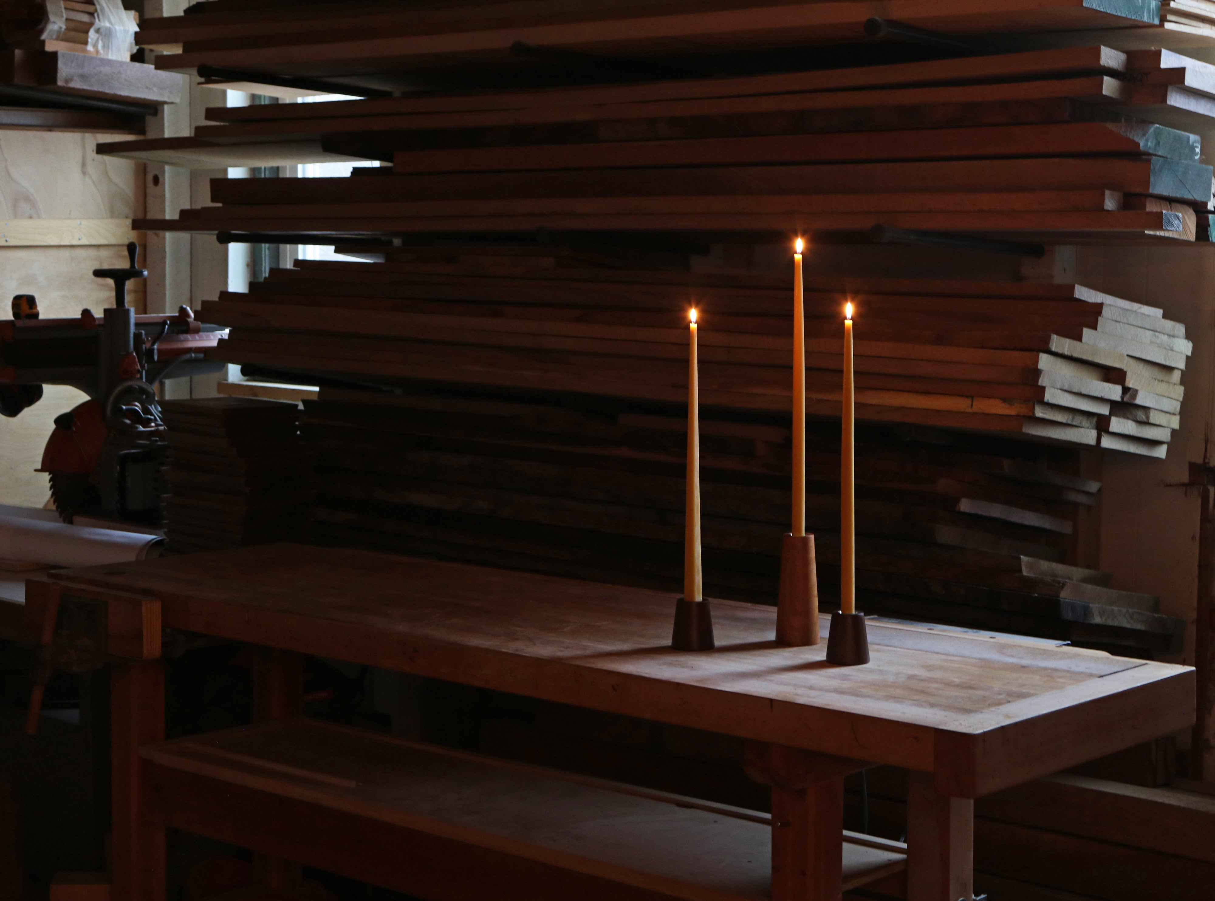 Three tall candles on a wooden table with a dark background