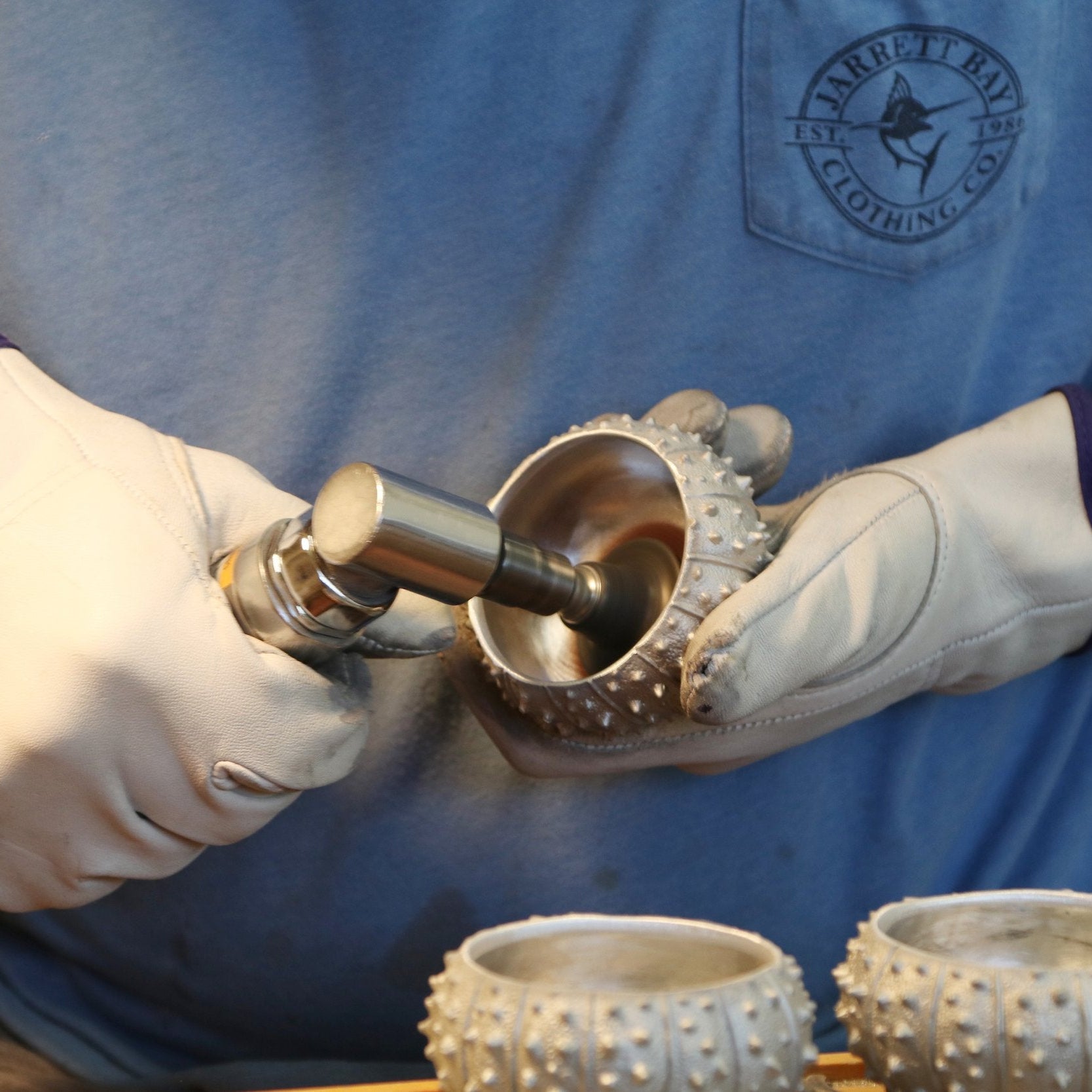 hands polishing silver sea urchin bowl