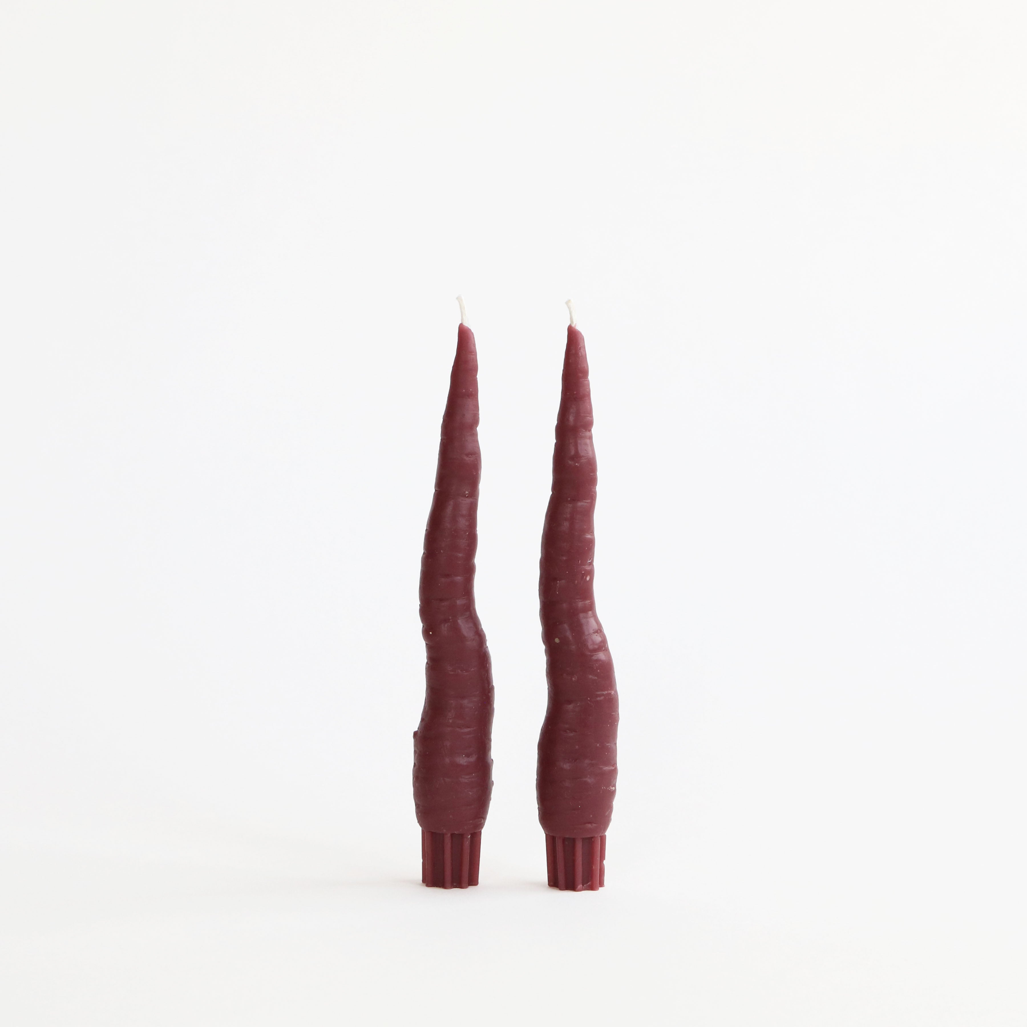 Two tall, thin burgundy candles on a white background