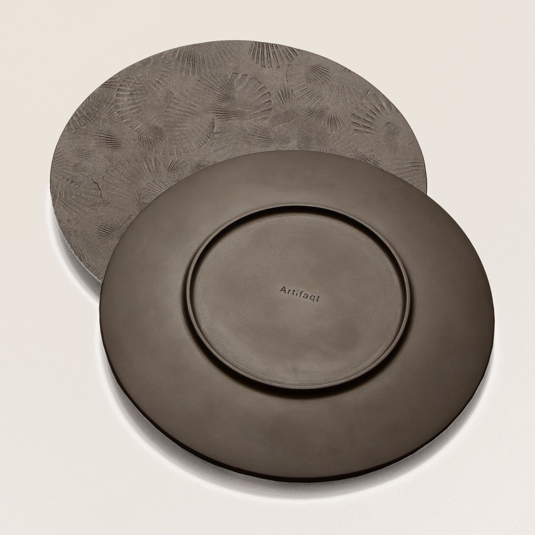 front and back of round black metal serving tray with scallop impressions