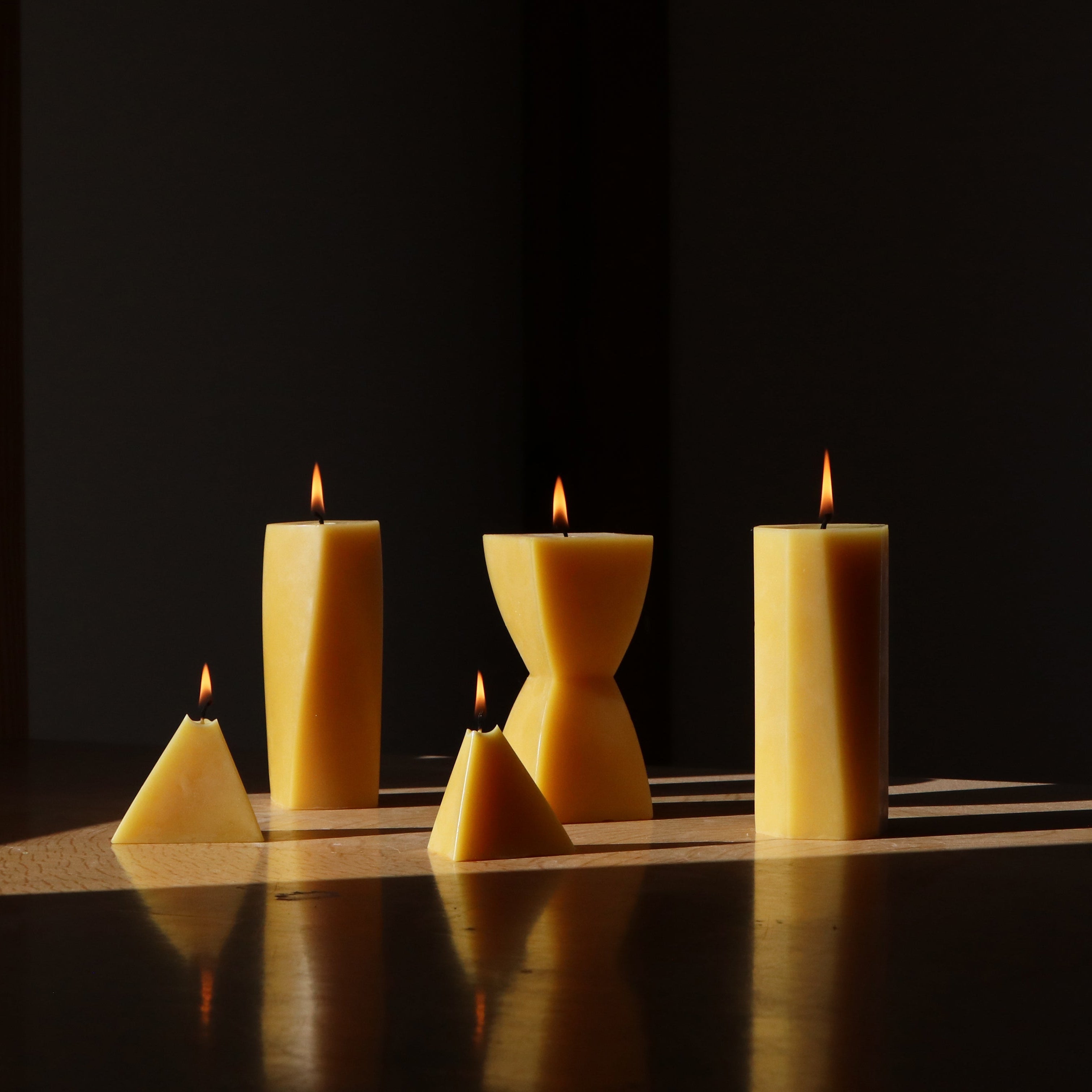 Five different shaped candles lit on a dark background