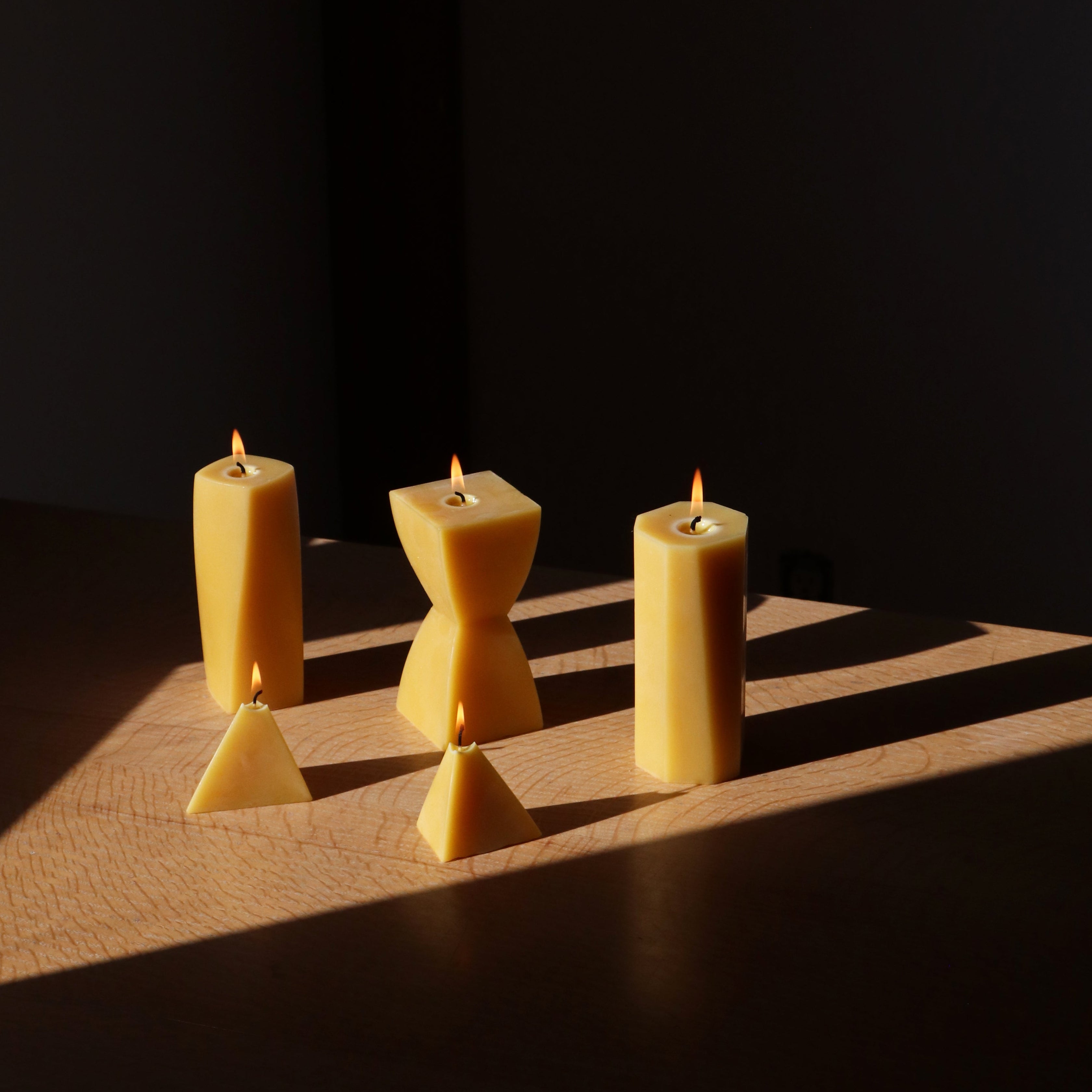 five beeswax candles lit on dark background