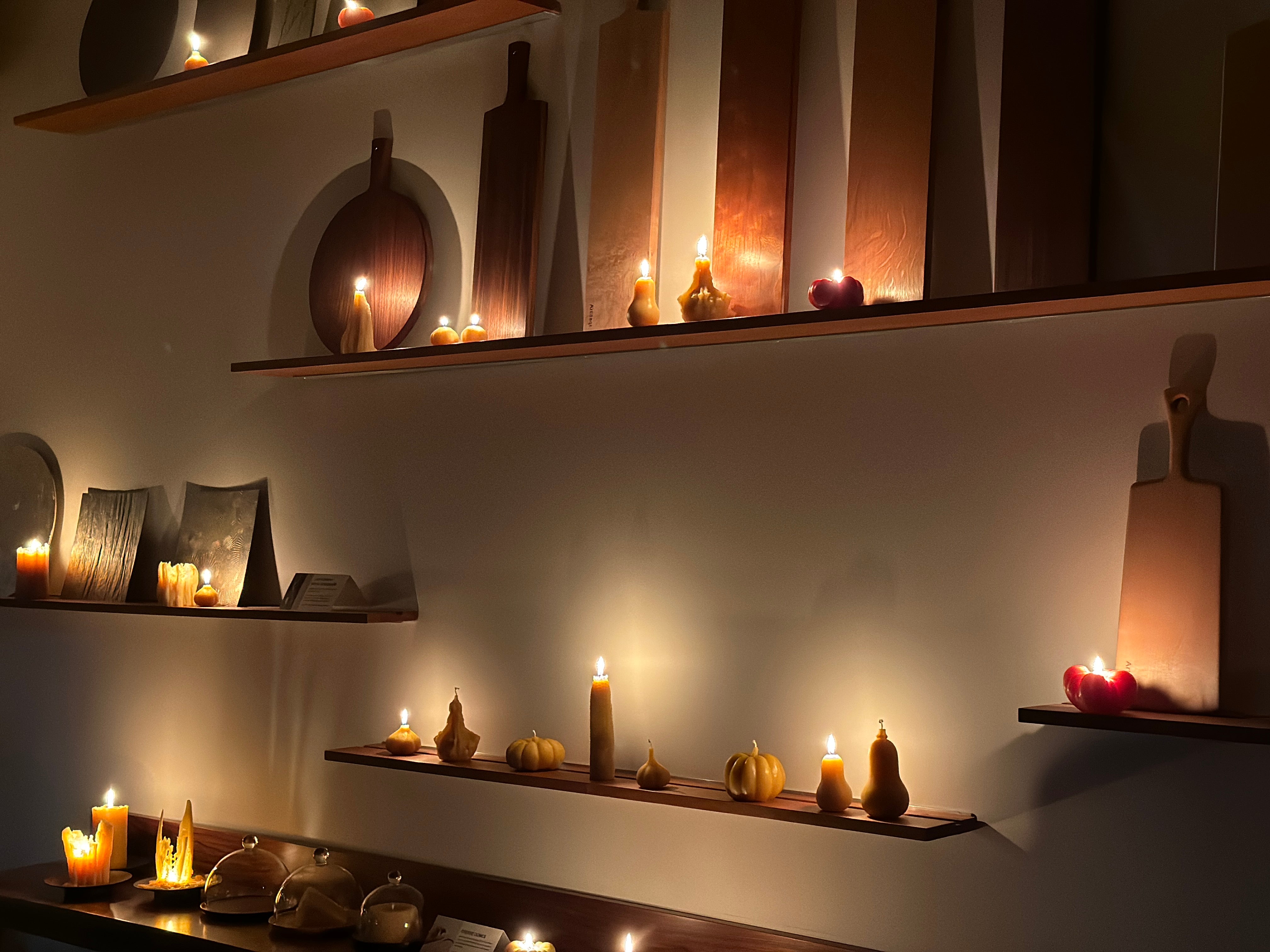 Decorative shelves with candles and decorative items against a wall.