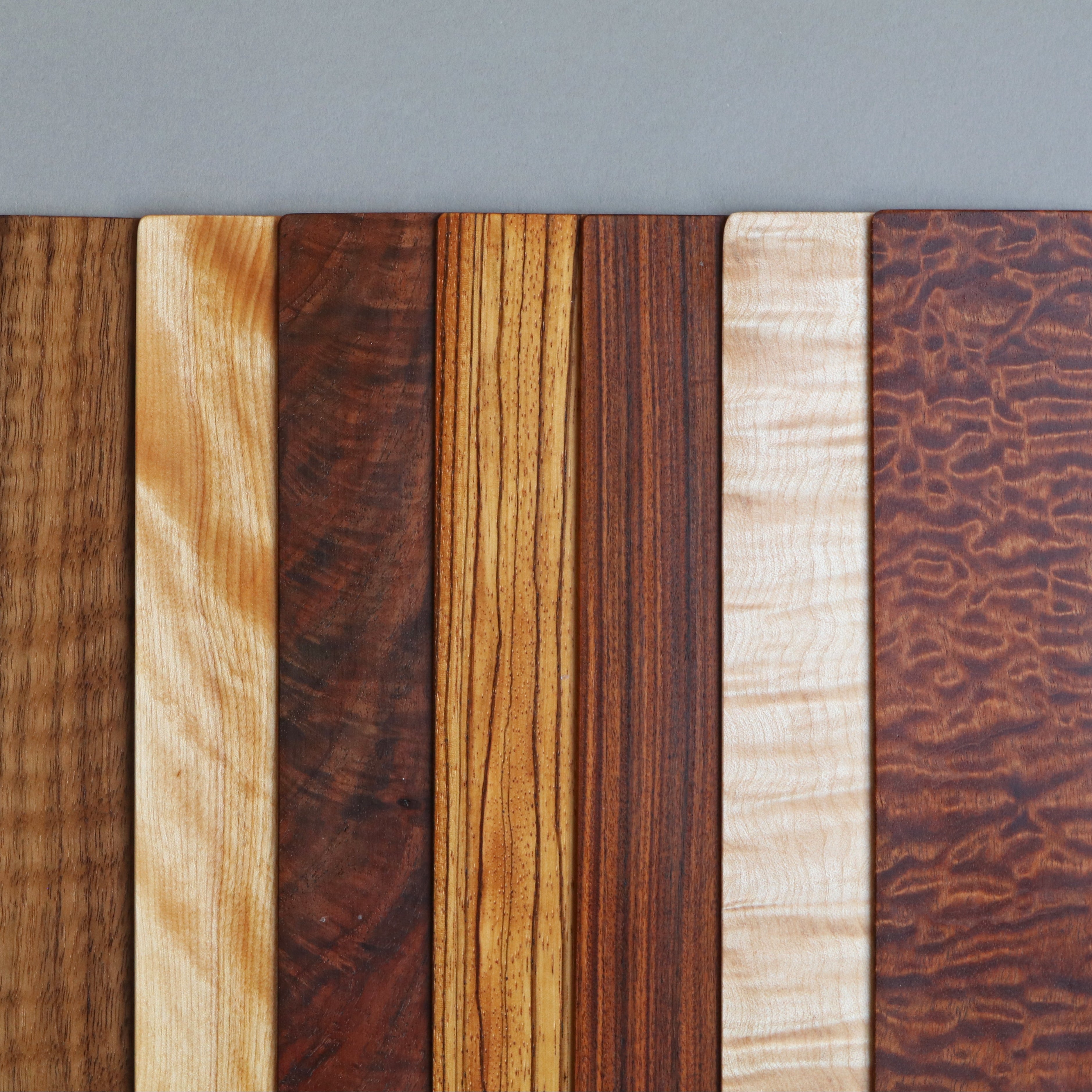 Five wooden samples with different textures and colors on a gray background