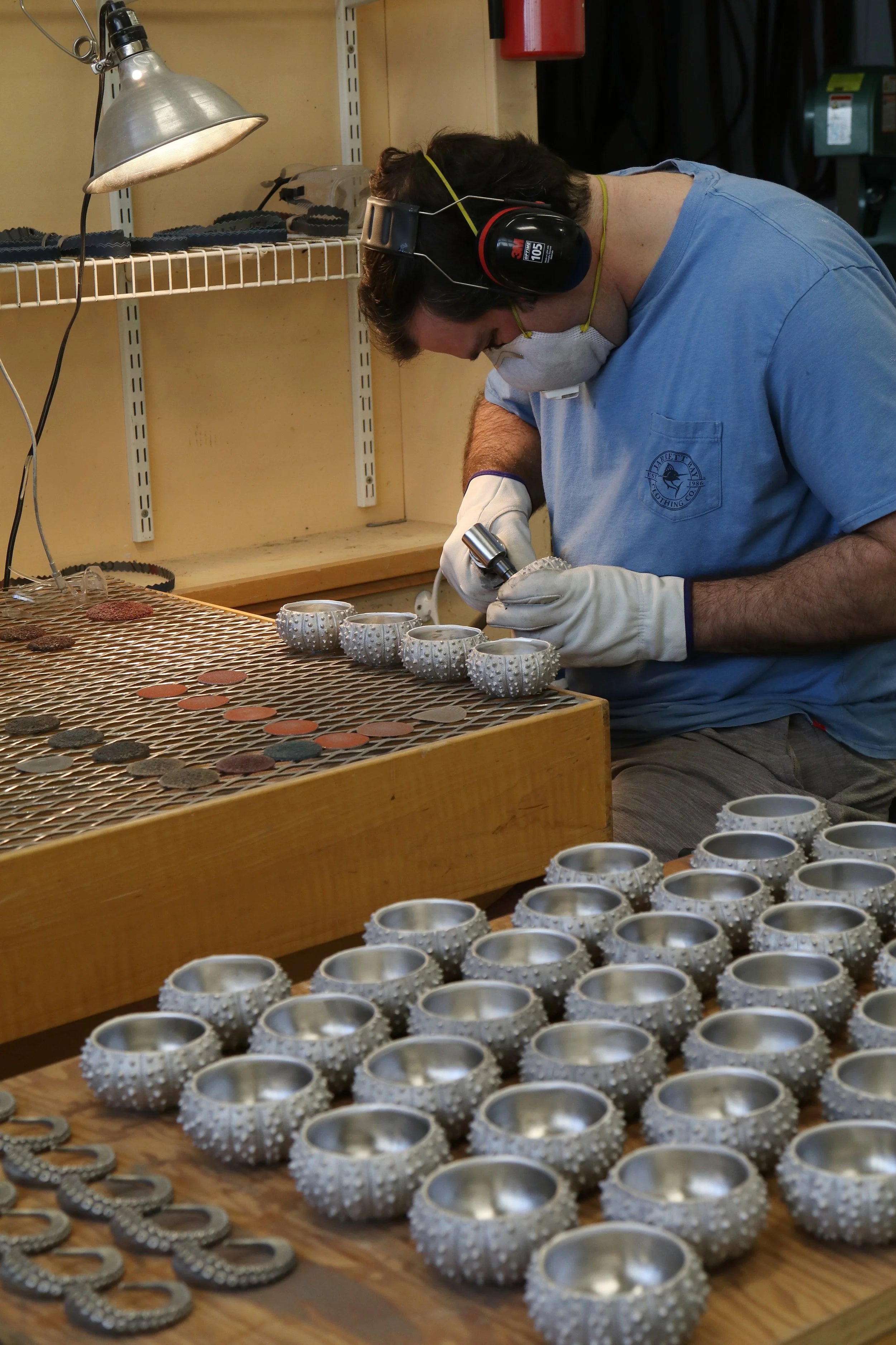 Person working on small metal bowls in a workshop setting
