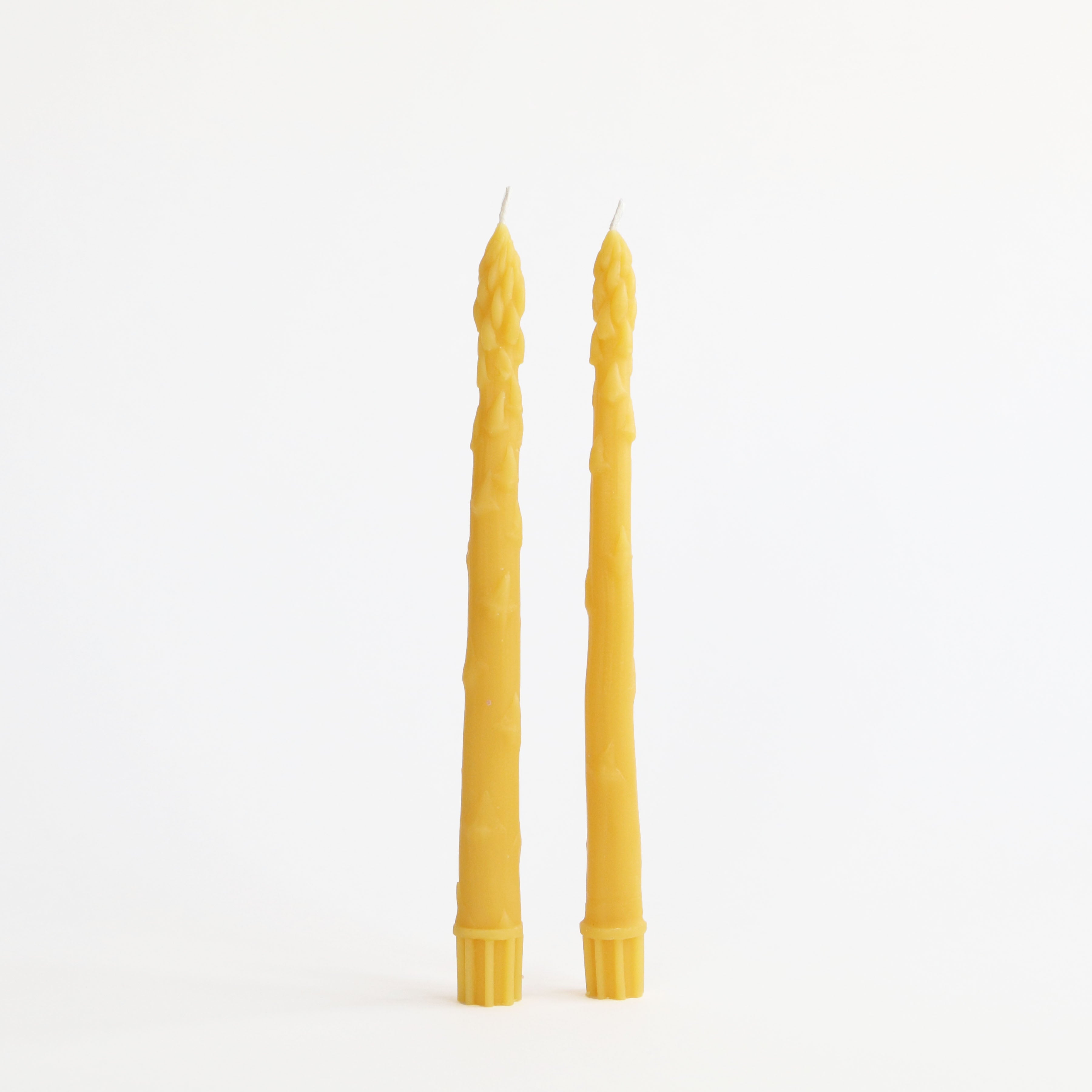 Two yellow candles with textured design on a white background